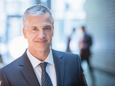 A businessman in a suit and tie is smiling.