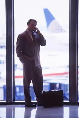 A man in a suit is talking on the phone in an airport.