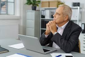 A man in a suit sitting at a desk with a laptop.